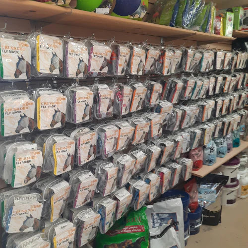 Shelves filled with various horse fly masks packaged in clear bags. The orderly display creates a sense of abundance and organization in a store setting.